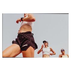 two women are playing frisbee against each other in the air while another woman watches