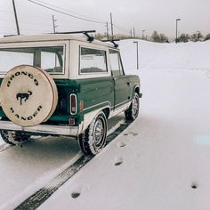 a green and white truck parked in the snow