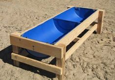 a wooden bench made out of pallets with a blue plastic bowl on the bottom