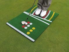 a person standing on top of a green mat with a golf ball and tee in it