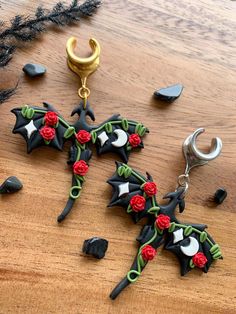 a pair of black and red earrings sitting on top of a wooden table next to other items