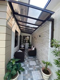 an outdoor covered patio with two couches and potted plants on the side walk