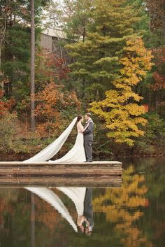 a bride and groom standing on a dock in the water