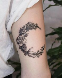 a black and white photo of a flowered crescent tattoo on the right arm with flowers around it