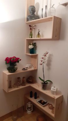 three wooden shelves with vases and flowers in them on the wall next to each other