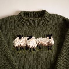 a green sweater with three sheep on it