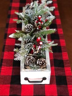 a red and black checkered table cloth with pine cones, evergreens and berries