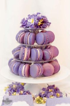 purple macaroons are stacked on top of each other with flowers in the middle