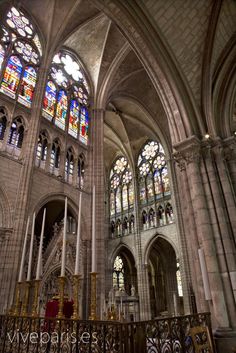 the interior of a cathedral with stained glass windows and wrought iron railings on either side