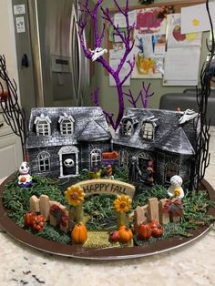 a cake decorated with halloween decorations on a table in front of a house and tree