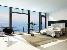 a bedroom with large windows overlooking the ocean