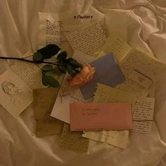 a rose is laying on top of some letters and papers that have been placed together