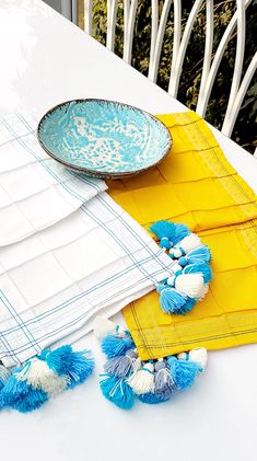 the table is set with plates, napkins and blue and white pom - poms