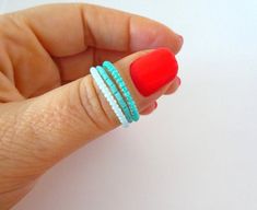 a woman's hand with red nails and turquoise bracelets on her thumb,