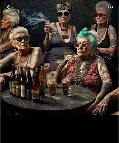 an old woman sitting at a table next to two older women with tattoos on their arms