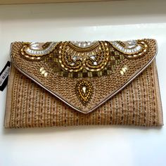 the purse is made out of woven material with gold and white beads on it's flap