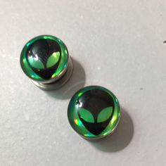 two green and black glass knobs on a white surface