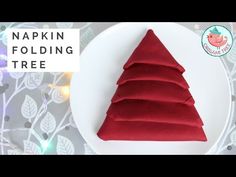 a red christmas tree on a white plate with the words napkin folding tree below it