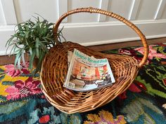 a wicker basket holding a magazine and a potted plant on a colorful rug