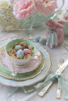 a tea cup filled with small eggs on top of a saucer next to flowers