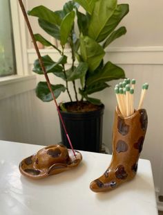 a pair of boots with toothpicks in them sitting on a table next to a potted plant