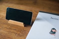 a cell phone sitting on top of a wooden stand next to a paper and envelope