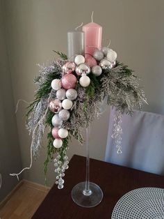 a tall glass vase filled with christmas decorations and candles on top of a wooden table