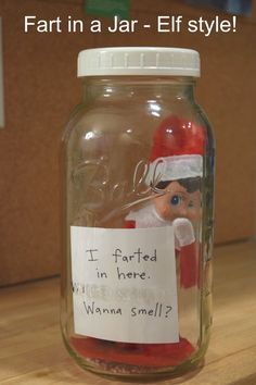 a glass jar with a santa clause in it and a sign that says, i fart in a jar - elf style