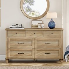 a wooden dresser with a mirror on top of it next to a lamp and window