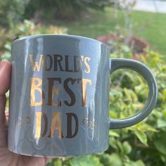 a person holding up a coffee mug with the words world's best dad on it