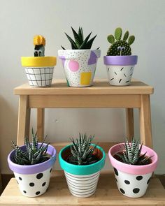 four potted plants sitting on top of a wooden shelf next to each other in different colors