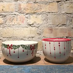 two bowls sitting next to each other on top of a wooden table in front of a brick wall