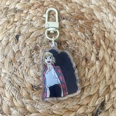 a keychain with an anime character on it sitting on top of a woven basket