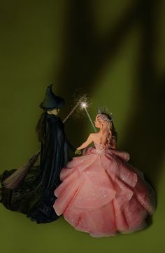 two figurines one in a pink dress and the other in a black gown