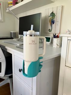 a white desk with a computer on it and a cup holder attached to the top