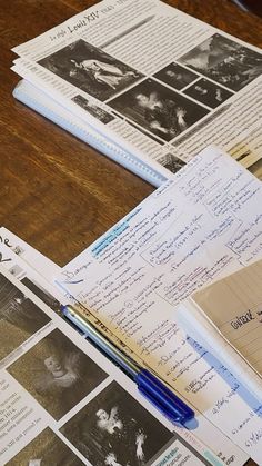 some papers and pens are laying on a wooden table with old photos, memos, and writing utensils