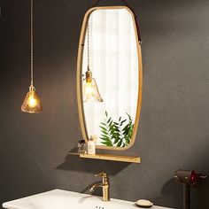 a bathroom sink sitting under a mirror next to a light hanging from a hook on the wall