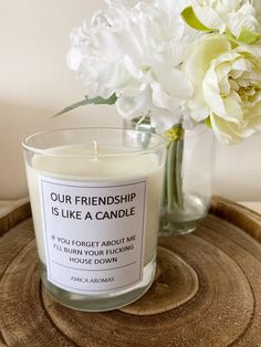 a candle sitting on top of a wooden table next to a vase with white flowers