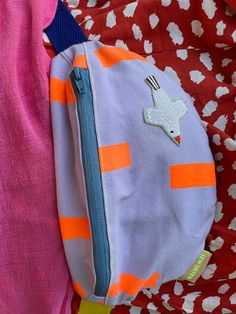 an orange and pink purse sitting on top of a bed