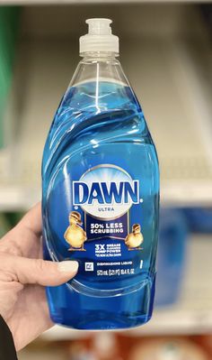 a hand holding a bottle of dawn dishwasher detergent in front of a store shelf