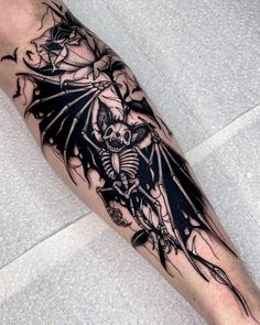 a man's leg with a black and white tattoo design on it, featuring a bat