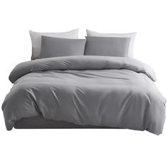 a bed with grey sheets and pillows on it