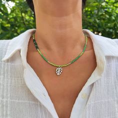 Elevate your style with this stunning handmade tropical green beaded necklace, crafted with love and meticulous attention to detail. It features a harmonious blend of colorful green and silver glass beads, accented by the elegance of natural Aventurine stones. The highlight is a tropical philodendron leaf pendant that adds a touch of nature's beauty to your attire.  Perfect for nature lovers, this necklace captures the essence of the lush and vibrant world. Each bead and stone has been thoughtfu Bohemian Green Crystal Necklace With Colorful Beads, Handmade Bohemian Green Emerald Necklace, Handmade Green Bohemian Emerald Necklace, Handmade Adjustable Green Emerald Necklace, Green Beach Necklace With Faceted Beads, Green Faceted Beads Necklace For Beach, Green Necklaces With Faceted Beads For The Beach, Green Necklace With Faceted Beads For Beach, Green Beaded Round Beads Emerald Necklace