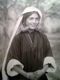 an old black and white photo of a woman wearing a nun's outfit with large hoop earrings