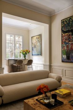 a living room filled with furniture and a painting on the wall next to a coffee table