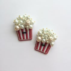 two red and white pins with pearls on them sitting next to each other in front of a white background