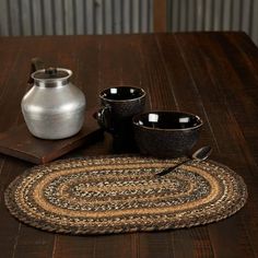 a wooden table topped with two bowls and a silver jug on top of a rug