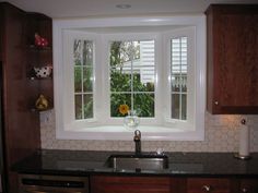 a kitchen with wooden cabinets and white windows