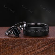 two wedding bands and an engagement ring sitting on top of a wooden table