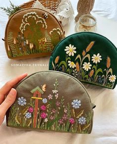 three embroidered purses sitting on top of a bed